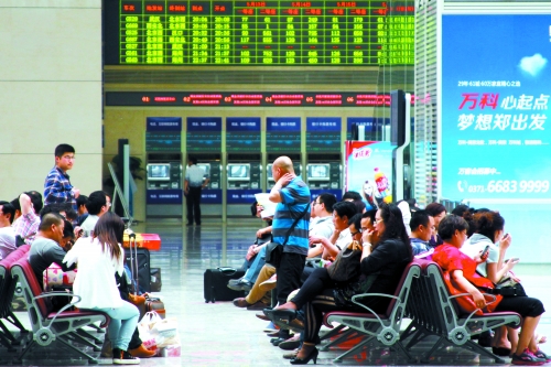 候車大廳溫度很高，一名乘客一手扇風、一手擦汗